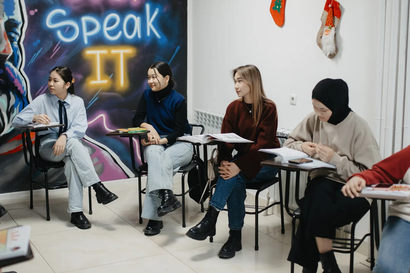 Студенты JSI в классе с неоновой вывеской Just Speak It